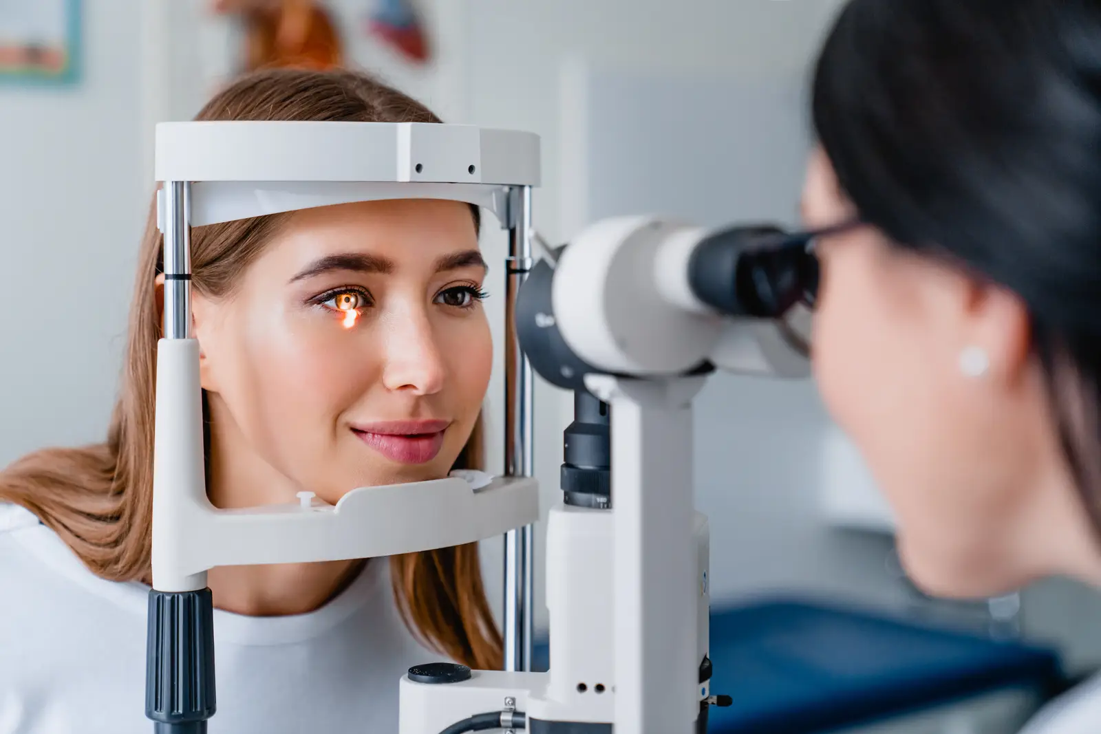 A woman is having her eyes examined by an optometrist in an office.